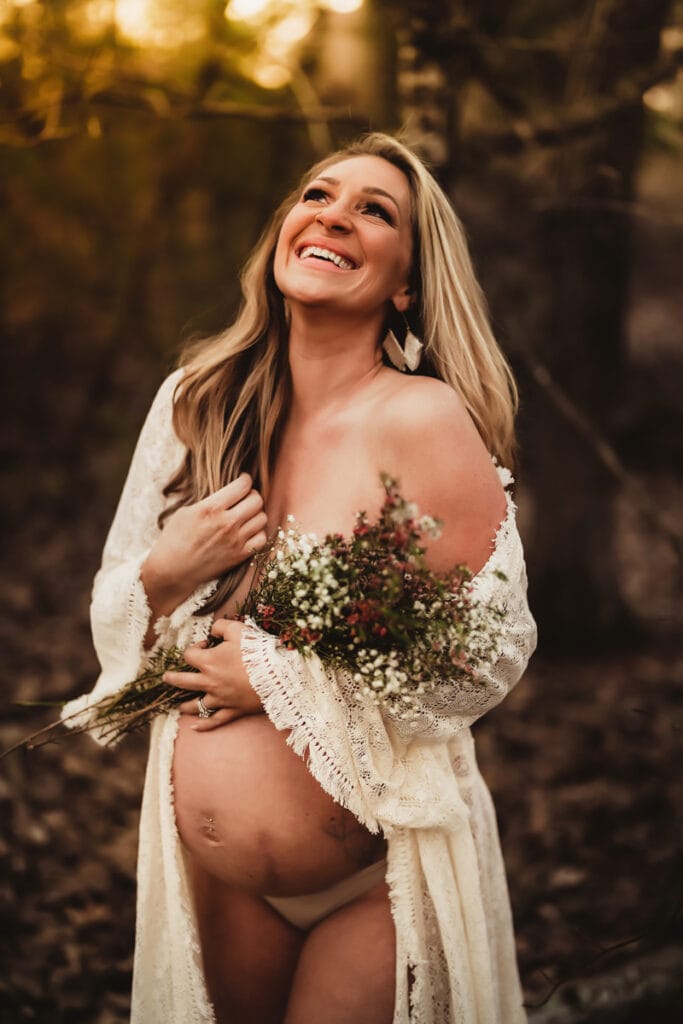 Maternity Photographer, a pregnant woman smiles holding a bouquet of flowers